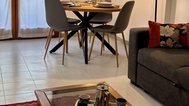 A dining area with a table set for four, a sofa, a coffee table with a tray, and a painting on the wall. - Soleja House, 1000 meters from Poetto beach and Molentargius Park (Quartu Sant'Elena)