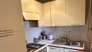 A compact kitchen with a gas stove, oven, sink, and light fixtures. - Soleja House, 1000 meters from Poetto beach and Molentargius Park (Quartu Sant'Elena)