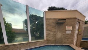 A swimming pool with a tiled floor, a glass enclosure, and a sign indicating it is for children. - Setor Bueno, Academia Piscina Órion Business (Goiânia)