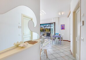 A modern interior with a dining area, a kitchen counter, and a view through a glass door. - *Rooftop Pool* · Apartment 150m from the Sea (Marina di Pietrasanta)