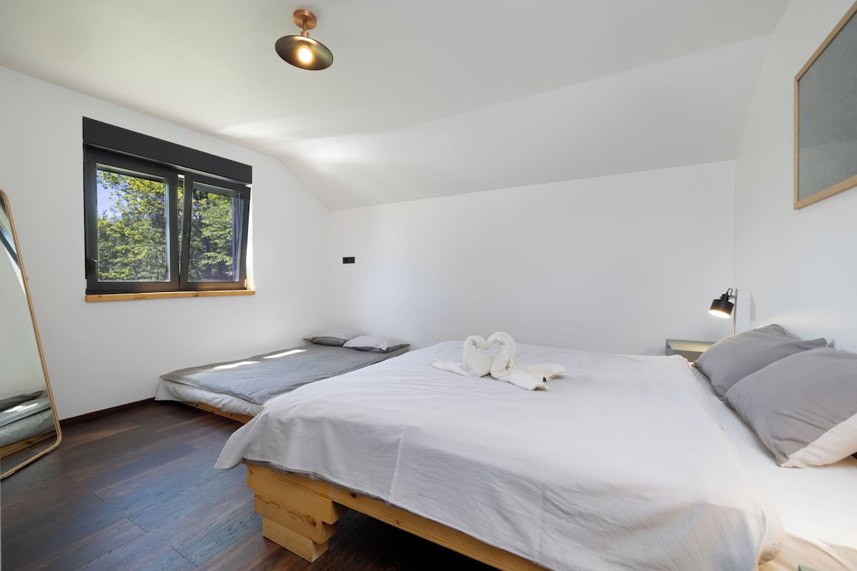Une chambre avec deux lits, une fenêtre, un miroir et un luminaire au plafond.