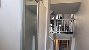 En gang med spejlvæg, trappe og et lille siddeområde med sko.
