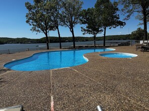 Ein Pool mit Kiesplattierung, umgeben von Bäumen und mit Blick auf ein Gewässer.