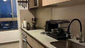 Una cocina moderna con encimera de granito, pileta de acero inoxidable y muebles de madera.