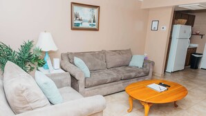 Uma sala de estar com um sofá, uma mesa de centro, um abajur e um quadro na parede.