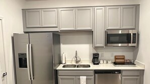 A compact kitchen with a refrigerator, microwave, sink, and dishwasher.