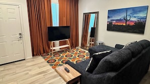 A living room with a sofa, TV, and a painting on the wall.