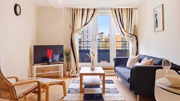En moderne stue med fjernsyn, sofa og spisebord.