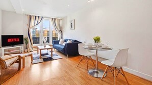 En moderne stue med sofa, fjernsyn, spisebord og stole.