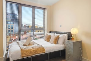 Ein Schlafzimmer mit einem Bett, einem Nachttisch und einem Fenster mit Jalousien.