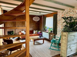 A cozy living room with a brick fireplace, wooden beams, a sofa, a coffee table, and a rocking chair. - Mediterranean cottage of Guesthouse In the Monkey - Casa del Vecino - Hartje Bergen (Bergen)