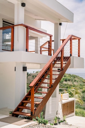 A modern multi-level house with a wooden staircase connecting the floors. - Villa Tortuga - Oceanview House with Heated Pool (Culebra)