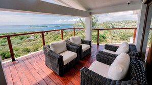 A balcony with wicker furniture and a view of the ocean.