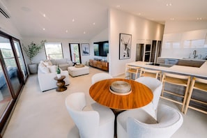 A modern kitchen with a central island, a dining area with a round table, and a living space with a sofa and a plant. - Villa Tortuga - Oceanview House with Heated Pool (Culebra)