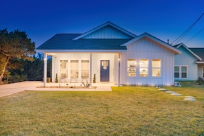 A modern two-story house with a covered porch, large windows, and a well-maintained lawn.