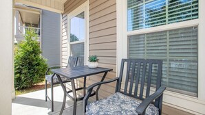 An outdoor patio with a table and two chairs, a small potted plant, and a view of the house through large windows. - 4BR/3BA, 3700 SqFt, Luxury Home in Durham near RDU, Duke, and UNC (Durham)