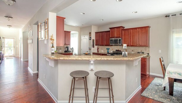 A spacious kitchen with a central island, wooden cabinets, and a stainless steel microwave. - 4BR/3BA, 3700 SqFt, Luxury Home in Durham near RDU, Duke, and UNC (Durham)