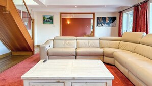 Un salon moderne avec un canapé d’angle, une table basse en bois et un escalier.