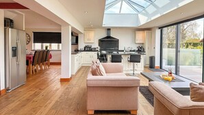 Un vaste espace de vie doté d’un haut plafond et d’une lucarne, une cuisine équipée d’appareils électroménagers modernes, et un coin repas avec une table et des chaises.
