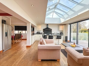 A spacious living area with a high ceiling and skylight, a kitchen with modern appliances, and a dining area with a table and chairs. - NEW - Ottersend Home w/ HotTub, Cinema & Fireplace (Chestfield)