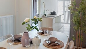 Ett matbord dukat med tallrikar, skålar, glas och en vas med blommor.