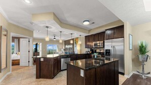 Une cuisine moderne avec des meubles en bois foncé, des appareils électroménagers en acier inoxydable et un grand îlot central.
