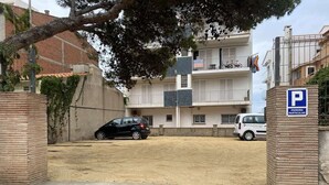 A parking area with a building in the background, a tree, and a sign indicating parking availability. - Spacious apartment with ocean view, 2 steps from the beach, ideal for families! (L'Escala)