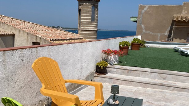 A rooftop terrace with a view of the sea, featuring a small tower, outdoor seating, and potted plants. - Spacious apartment with ocean view, 2 steps from the beach, ideal for families! (L'Escala)