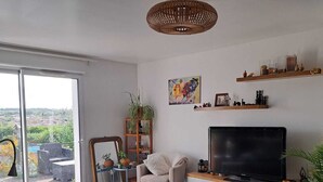 Een moderne woonkamer met een grote televisie, comfortabele zithoek, een eethoek en uitzicht door de glazen deur.