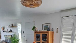 Een keuken met een centraal eiland, een eethoek met stoelen, een televisie en een kast met glazen deuren.