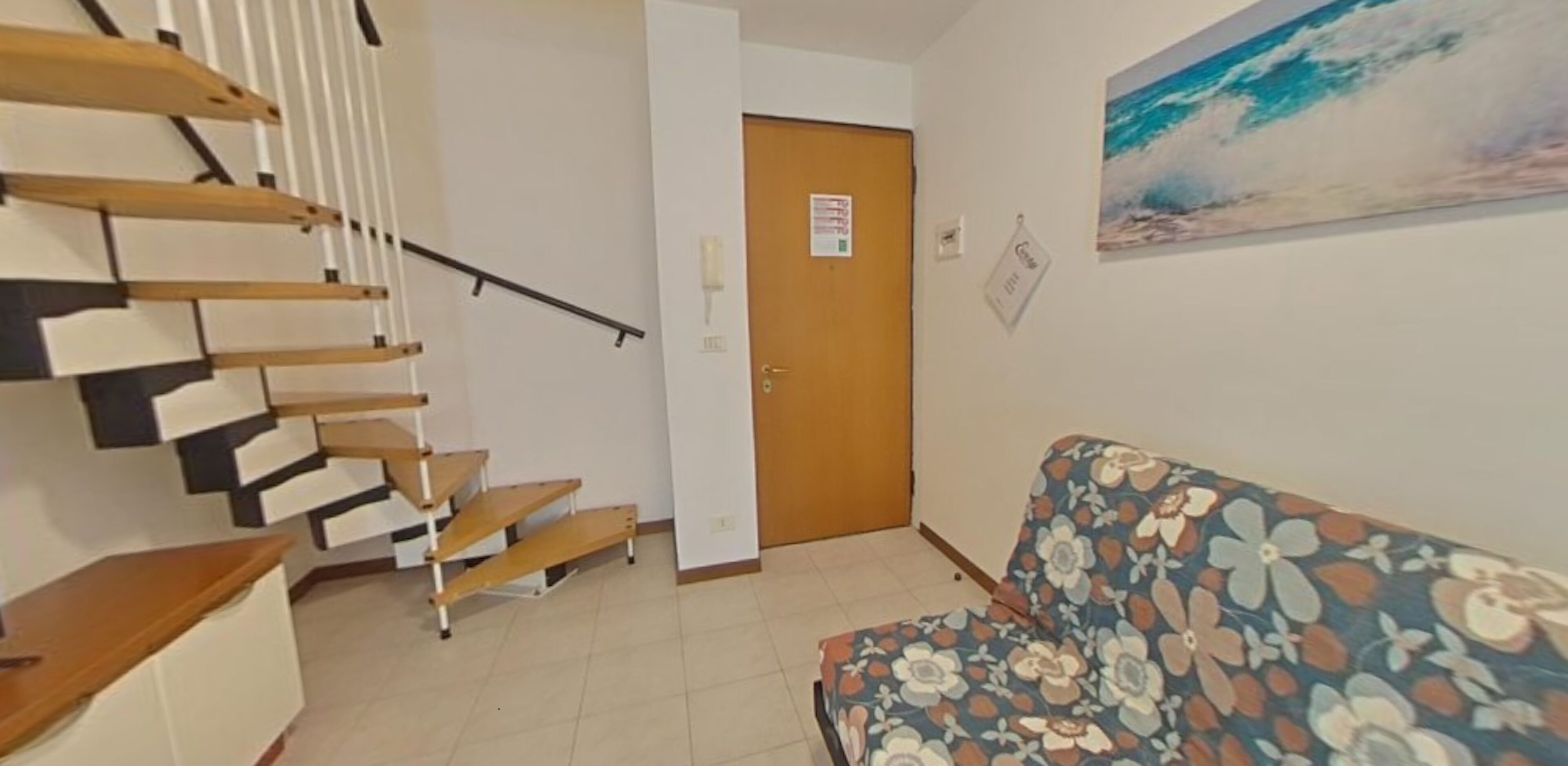 A staircase with wooden steps, a door with a sign, and a floral-patterned sofa.