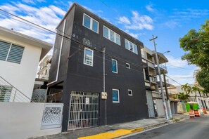 A multi-story building with a gated entrance, a visible security camera, and a street with construction barriers. - "La Placita" Apt. in San Juan! Santu2A (San Juan)