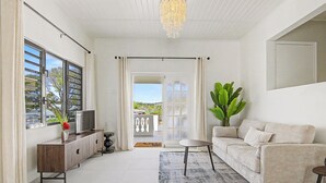 A modern living room with a sofa, TV, and a plant. - Villa Yuukas with private pool! Central location! (Willemstad)