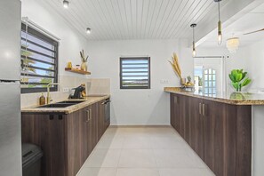 Eine moderne Küche mit dunklen Holzausziehtüren, einer weißen Arbeitsplatte und Blick durch ein Fenster.
