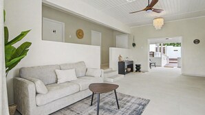 A spacious living area with a sofa, a coffee table, a ceiling fan, and a chandelier. - Villa Yuukas with private pool! Central location! (Willemstad)