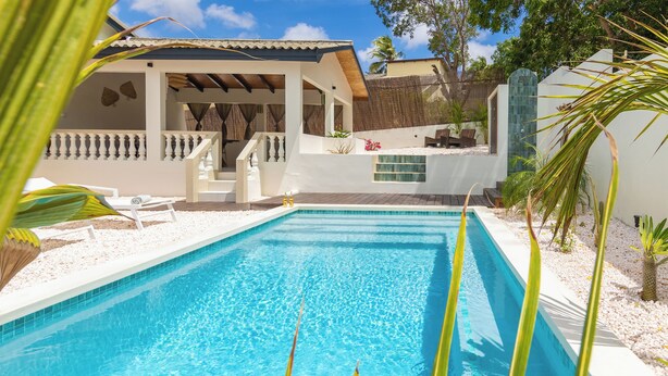 A swimming pool with a covered patio area, a small staircase, and a view of the surrounding landscape. - Villa Yuukas with private pool! Central location! (Willemstad)