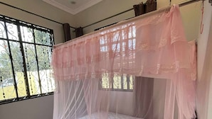 Ein Himmelbett mit einem Deckenventilator und einem Fenster mit Metallgitter.