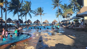 Ein Poolbereich mit Palmen, Sonnenschirmen und Liegestühlen.