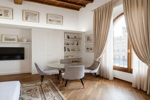 A room with a glass table, two chairs, a TV, a bookshelf, and a window with curtains. - (NEW) Piazza della Signoria View Luxury Apartment (Firenze)