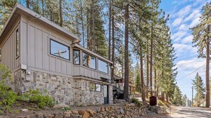 A two-story stone building with a stone wall foundation, large windows, and a staircase leading to a deck. - Kings Beach Cabin w/ Panoramic Lakeview & Forest (Kings Beach)