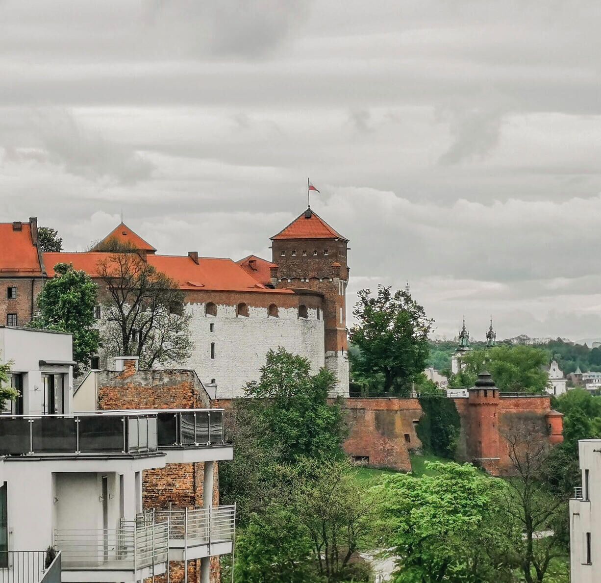Un château historique, doté d’une tour imposante, entouré de bâtiments modernes et de verdure.