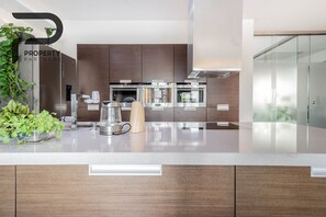 A modern kitchen with stainless steel appliances, wooden cabinets, and a glass backsplash. - Angel Plaza Kraków Apartment 140m2 / 5 minutes from the main square (Kraków)