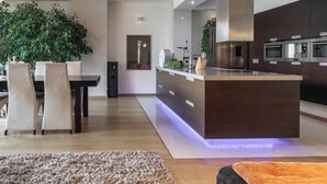 Una cocina moderna con una isla central, electrodomésticos integrados y un comedor con sillas y una mesa.