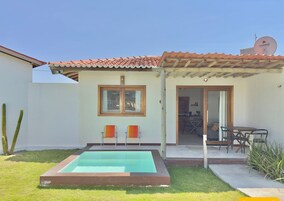 Uma casa com piscina, um pátio com cadeiras e uma antena parabólica.