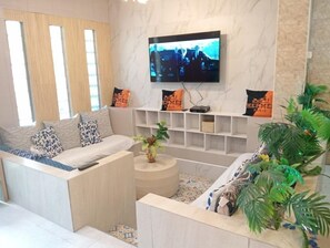 A modern living room with a sofa, a TV mounted on the wall, and decorative pillows.