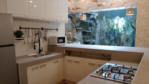Una cocina moderna con estufa a gas integrada, armarios blancos y un llamativo elemento decorativo tipo cascada sobre el lavamanos.