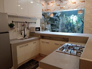 Une cuisine moderne dotée d’une cuisinière à gaz intégrée, de meubles blancs et d’un élément décoratif en forme de cascade au-dessus de l’évier.