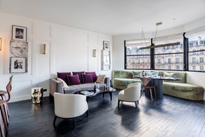 A modern living room with a sofa, chairs, a coffee table, and a dining area. - Victor Hugo Design - One Bedroom Apartment, Sleeps 2 (Paris)