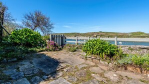 A stone pathway leading to a beach with a wooden fence and a small structure. - La Maison des Seigneurs les pieds dans l'eau (Le Conquet)