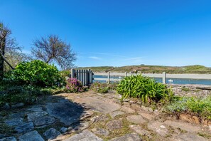 A stone pathway leading to a beach with a wooden fence and a small structure. - La Maison des Seigneurs les pieds dans l'eau (Le Conquet)